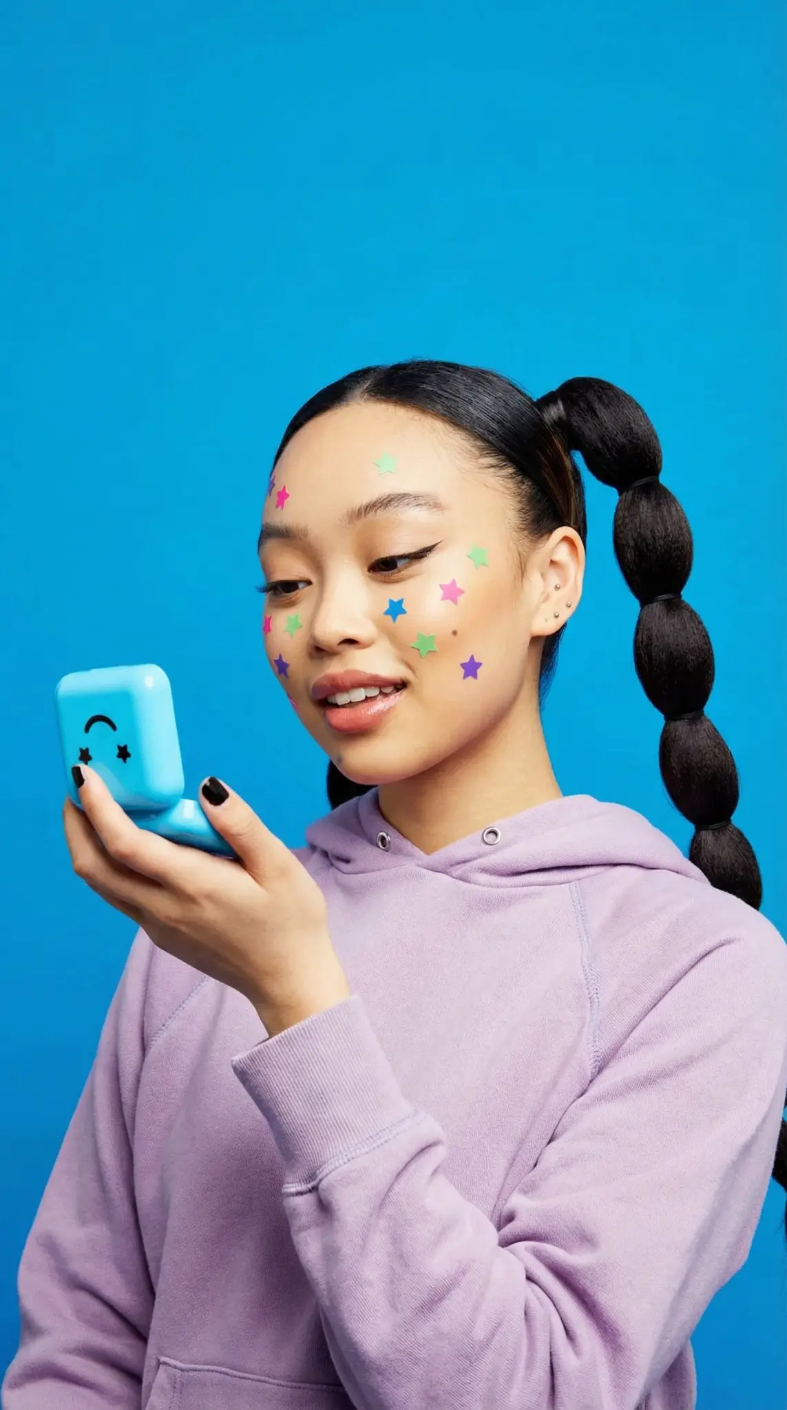 Starface Gen Z beauty campaign showing model in purple hoodie with colorful star patches and blue product case